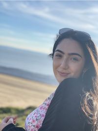 Portrait of a smiling young woman against sky