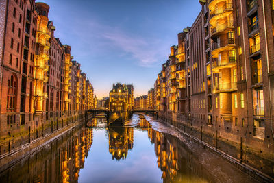 Reflection of buildings in city at sunset