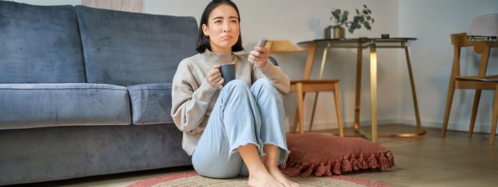 Portrait of young woman sitting on sofa at home