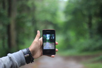 Midsection of person holding smart phone outdoors