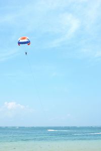 Person paragliding over sea against sky