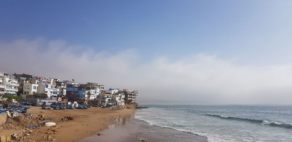 Scenic view of beach by buildings against sky