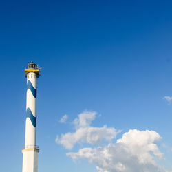 Low angle view of lighthouse by building against sky