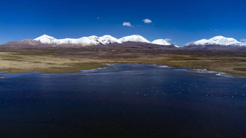 Scenic view of snowcapped mountains against blue sky