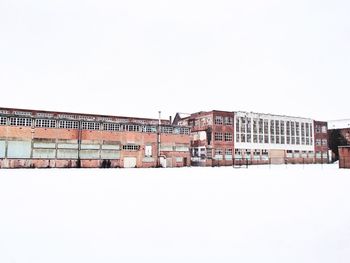 Buildings on snow covered field against clear sky