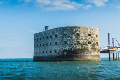 Built structure by sea against sky