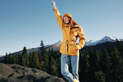 Young woman standing against mountain