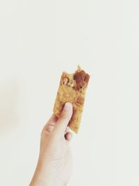 Close-up of hand holding bread against white background