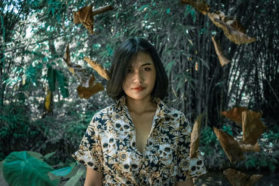 Portrait of young woman against trees in forest