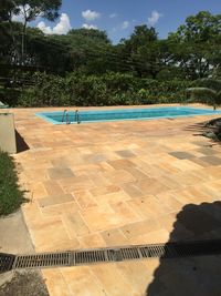 Swimming pool by trees against sky