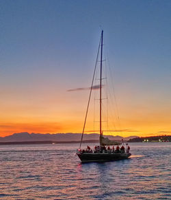 Sailboat sailing in sea at sunset