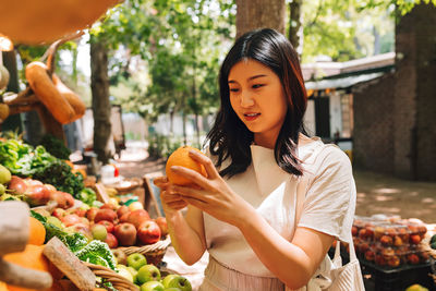 Portrait of young woman holding fruits at market