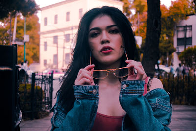 Portrait of beautiful young woman drinking water in city