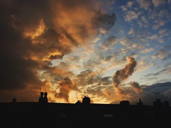 Low angle view of silhouette building against dramatic sky