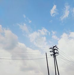 Low angle view of electricity pylon against blue sky