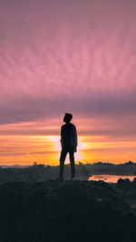 Silhouette man standing on shore against sky during sunset