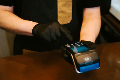 Midsection of man using mobile phone on table