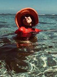 Woman wearing hat in sea against sky