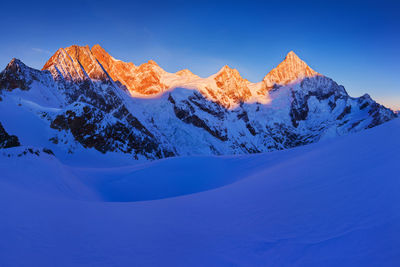 Scenic view of snowcapped mountains against clear blue sky