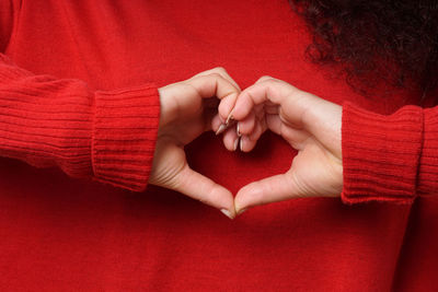 Midsection of woman making heart shape through hands