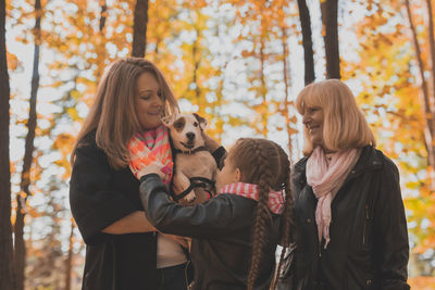 Rear view of friends standing against trees during autumn