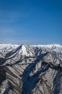 Scenic view of snowcapped mountains against blue sky