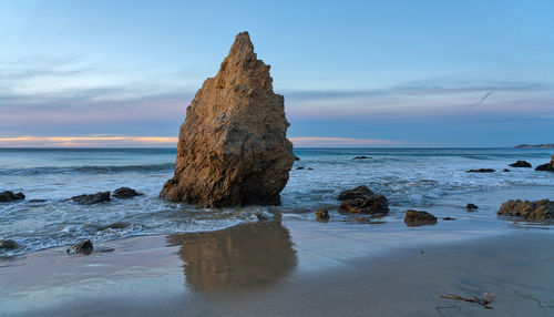 Rock formation on beach against sky