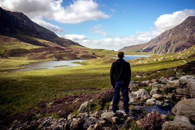 Rear view of man standing on landscape against sky