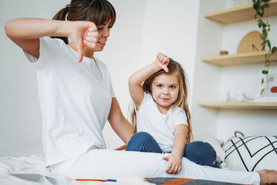 Woman looking at daughter showing thumbs down