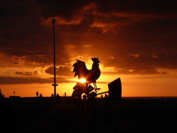 Silhouette people on beach against sky during sunset