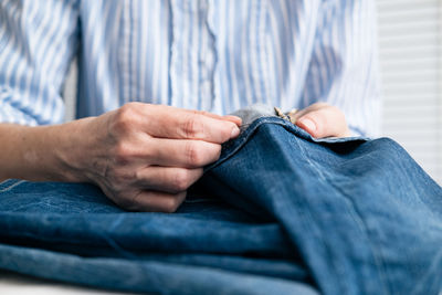 Midsection of craftswoman sewing jeans at workshop