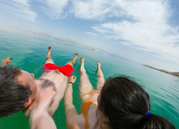 Couple swimming in sea against sky