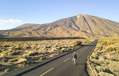 Man walking on road against mountain
