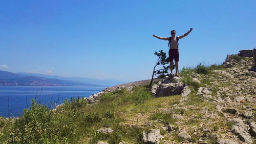 Man standing on rock against sky