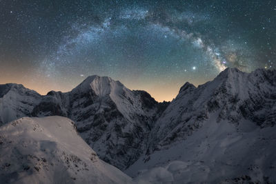 Scenic view of snowcapped mountains against sky at night