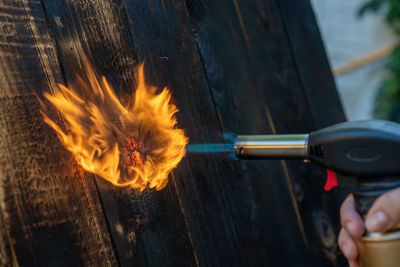 Cropped image of person holding fire on wood