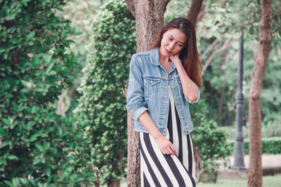 Portrait of smiling young woman standing by tree