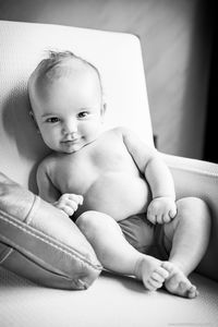 Portrait of cute baby boy sitting on sofa