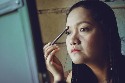 Portrait of young woman putting cosmetics