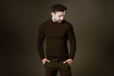 Young man standing against black background