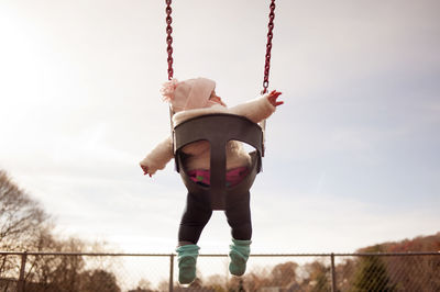 Low angle view of baby girl sitting on swing at park