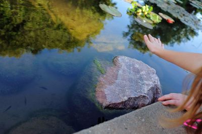 Midsection of woman on rock by lake