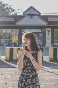 Portrait of woman standing against building in city