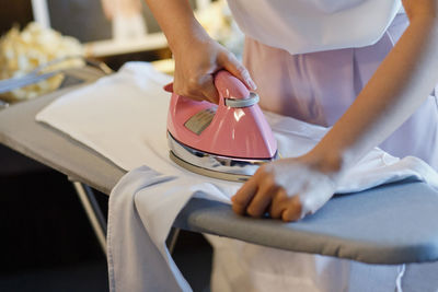 Midsection of woman ironing shirt