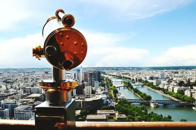 Coin-operated binoculars at observation point by cityscape against sky