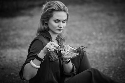 Midsection of woman holding camera while sitting on field