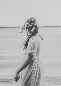 Portrait of smiling woman standing on beach