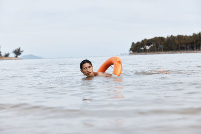 Portrait of woman swimming in sea against sky