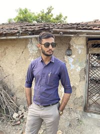 Portrait of young man standing against built structure