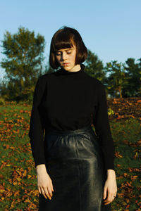 Young woman standing on field against clear sky